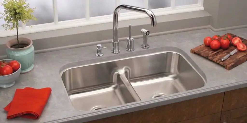 Elkay stainless steel kitchen sink & a chopped red tomato and red cloth beside it