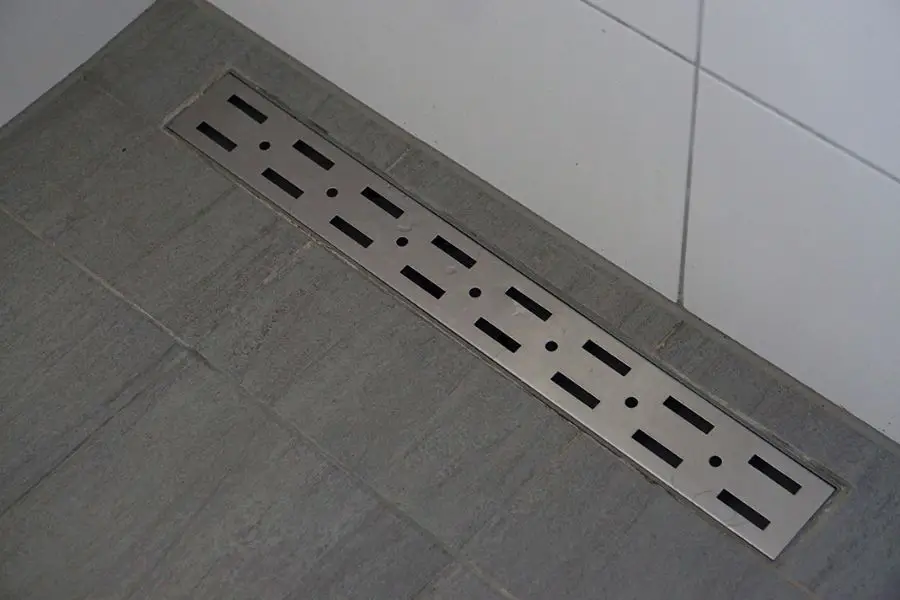 against the wall linear shower drain placement